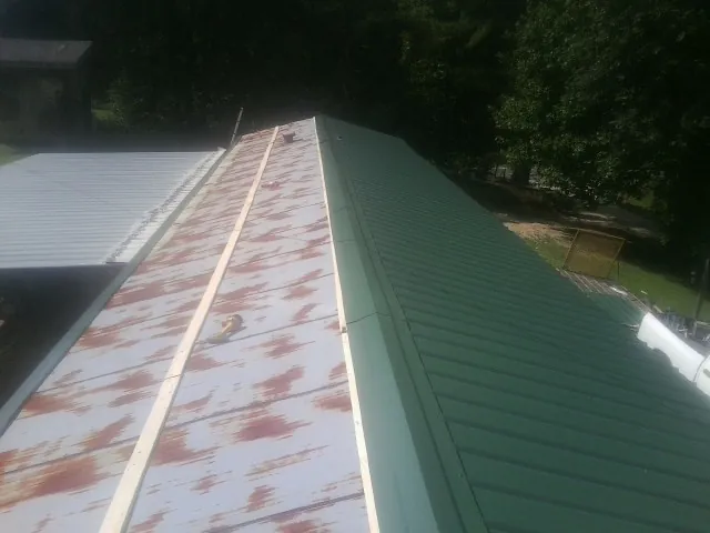 Old rusted panels beside newly installed green metal roofing — Wind Damage Roof Repair by Roofing Brothers in Mentone