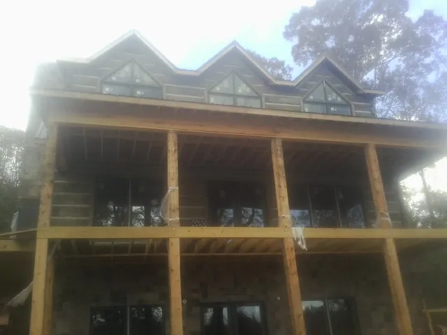 Dormers and porch framing on a large log home under construction — Roof Coating work by our crew in Mentone