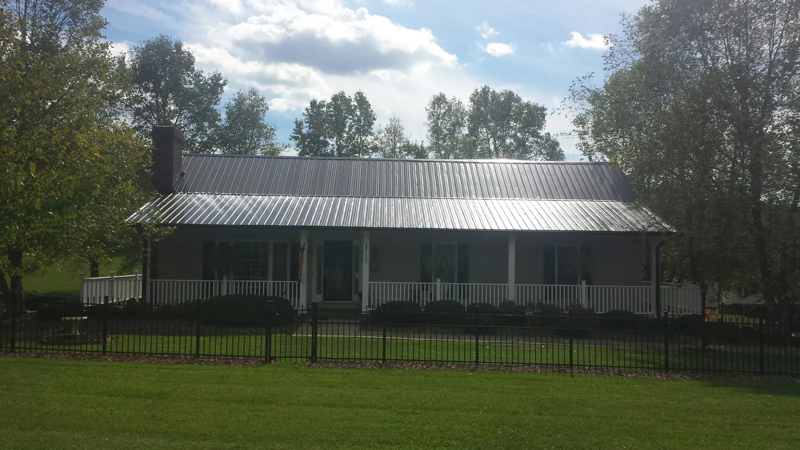Gray metal roof on a brick ranch with a full width front porch — Gutter Guard Installation work by our crew in Mentone