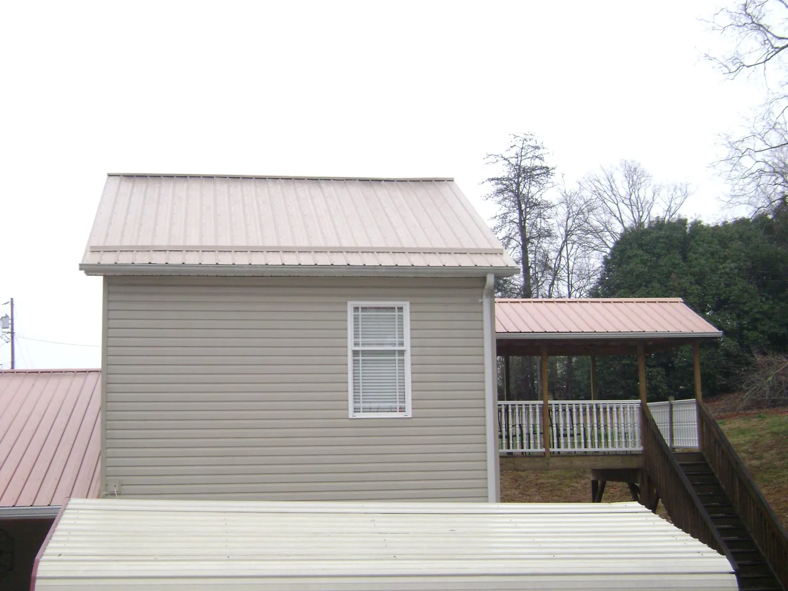 Tan metal roofs on a two story addition and attached porch, from a Roof Replacement job in Mentone